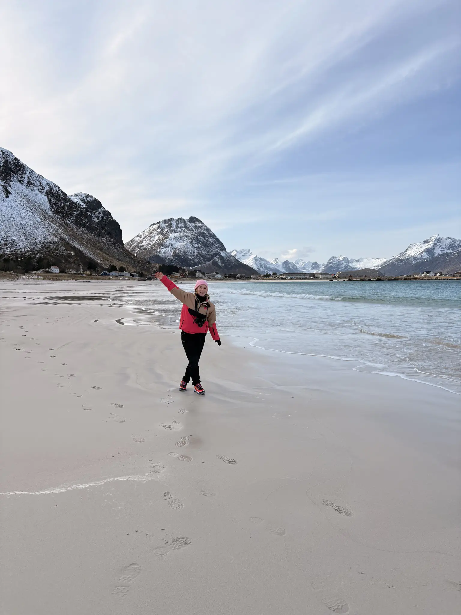 woman walking on a sandy beach with snowy mountains