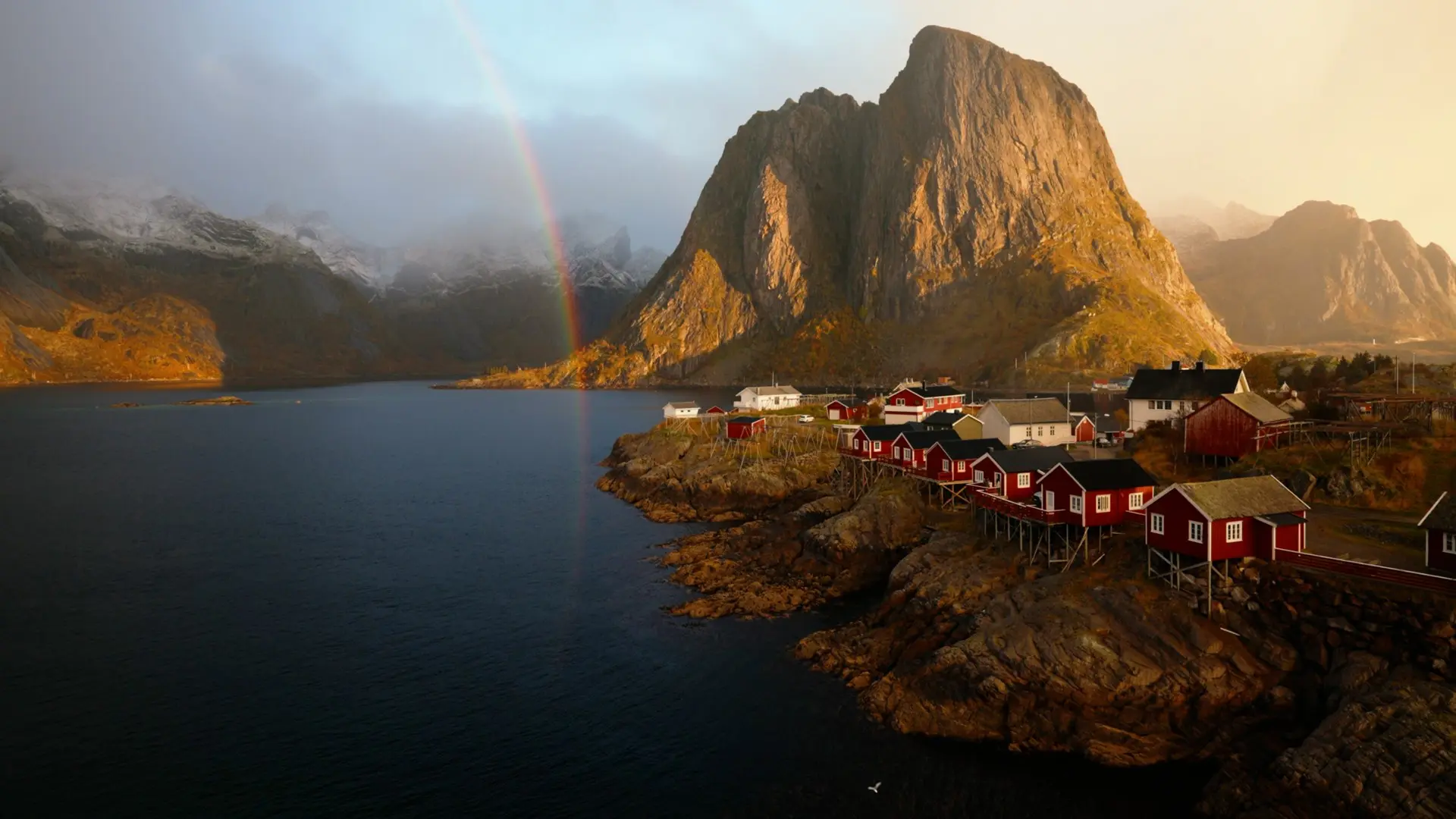rainbow over traditional red fishing village in Lofoten, Norway