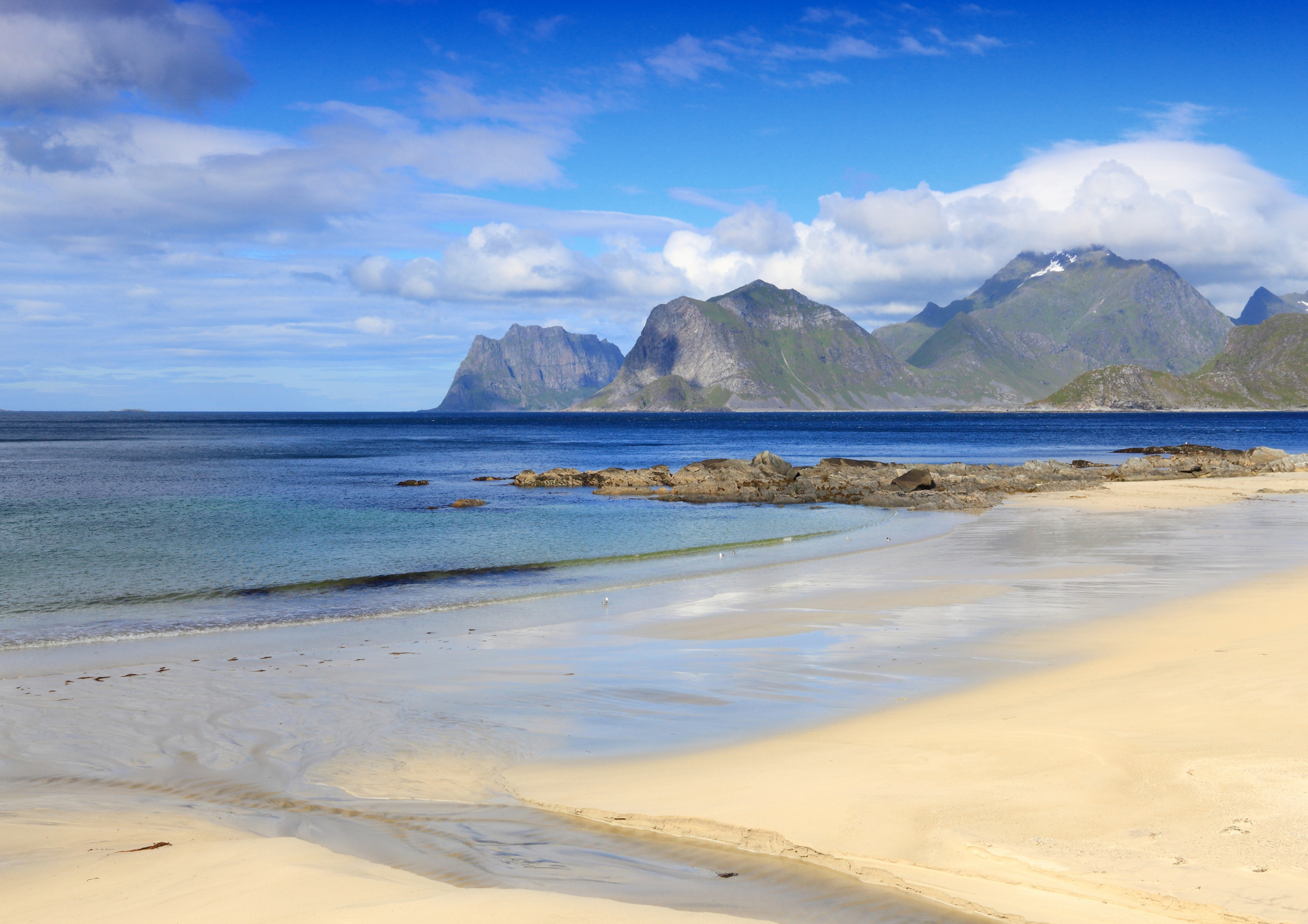 sandy beach with clear blue water and mountains in Lofoten, Norway
