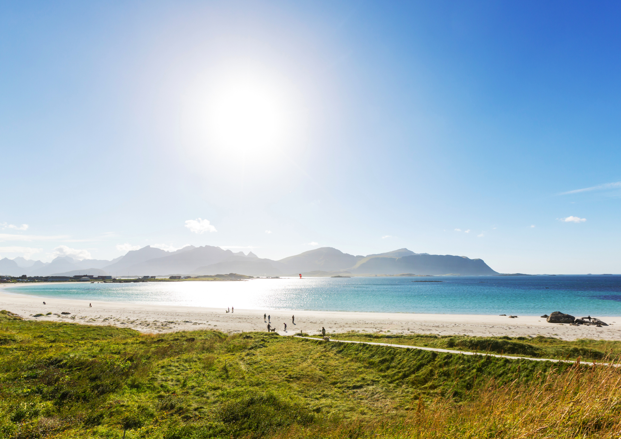 sunny beach with mountains and people in Lofoten, Norway