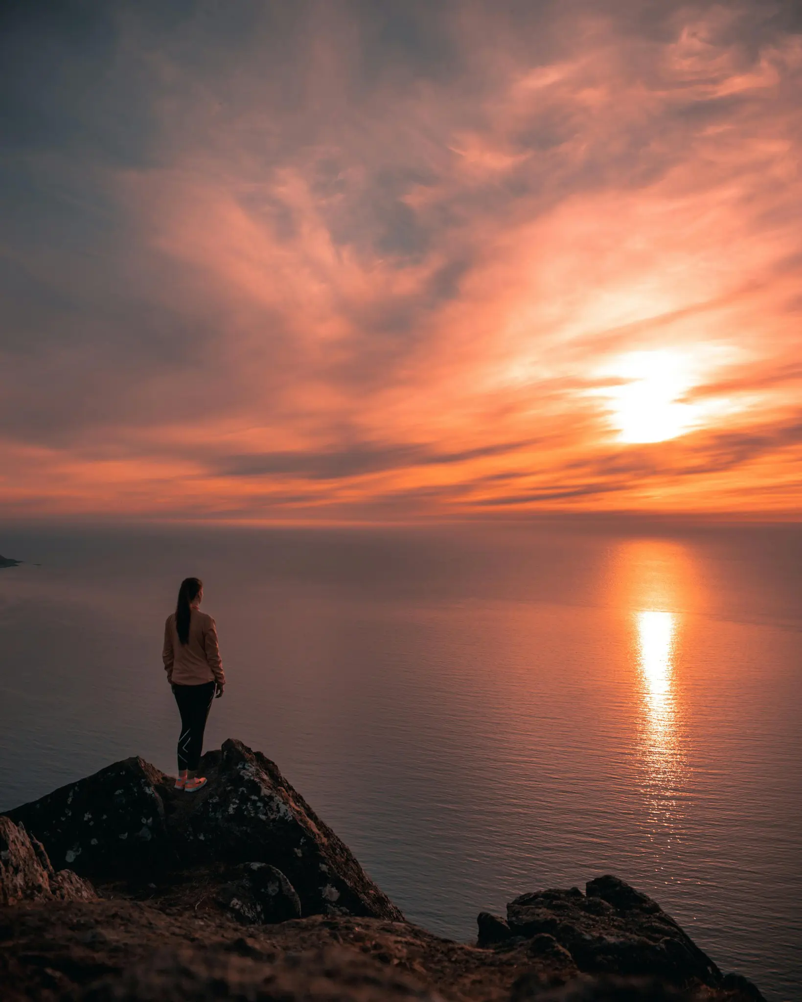 person watching sunset over the sea from a cliff